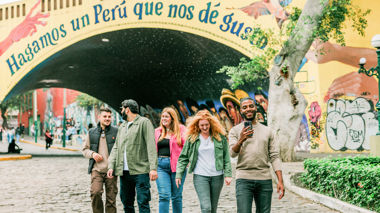 Travellers walking away from bridge covered in street art, Lima, Peru